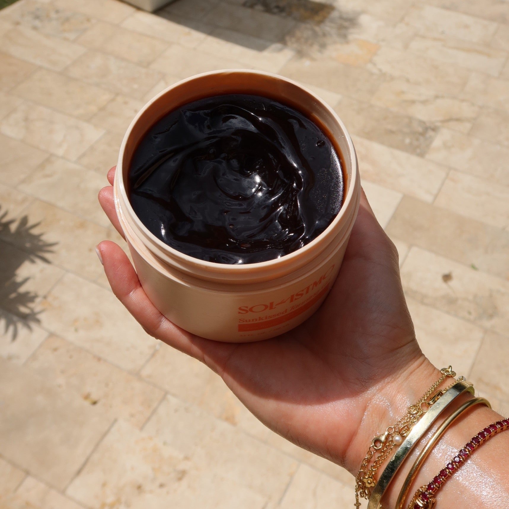 Open jar of Sunkissed Tanning Gel held in hand in the sun